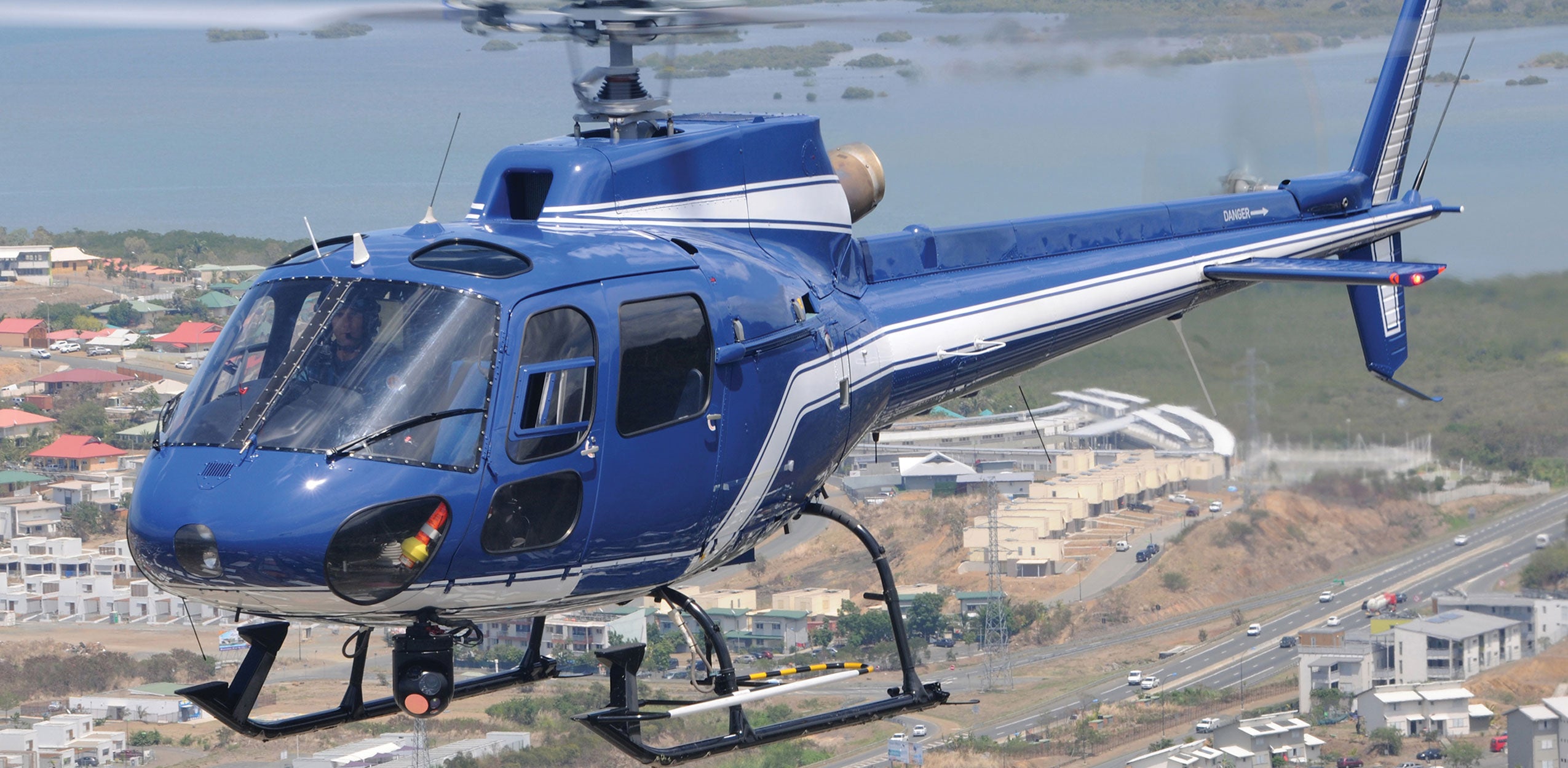 Helicopter flying above a city with a WESCAM MX-Series system mounted on the underbelly
