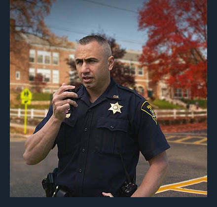 Police officer using portable radio near school