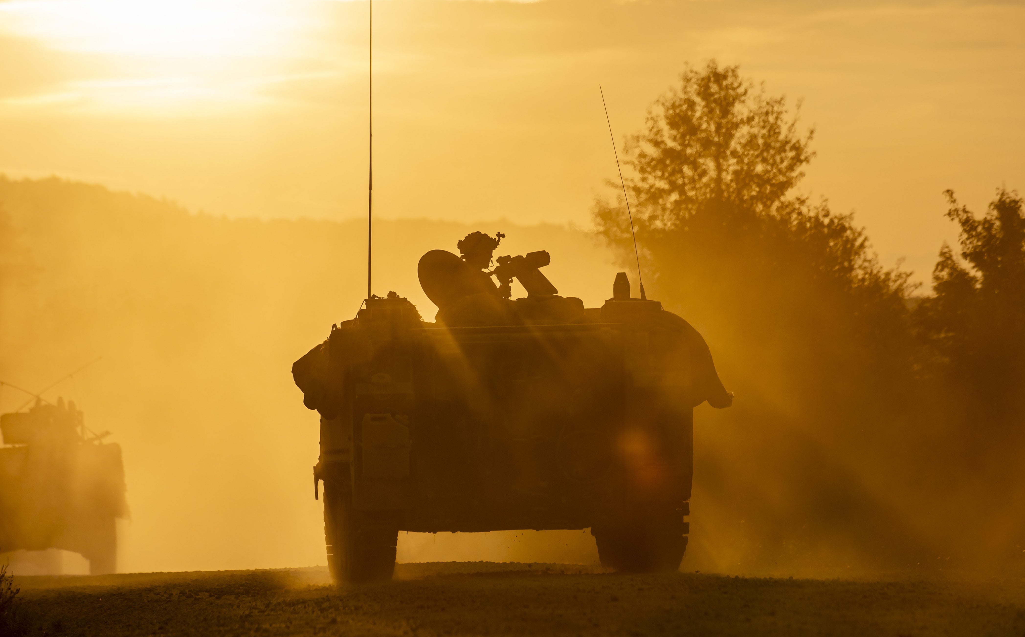 Troops ride a vehicle at dusk