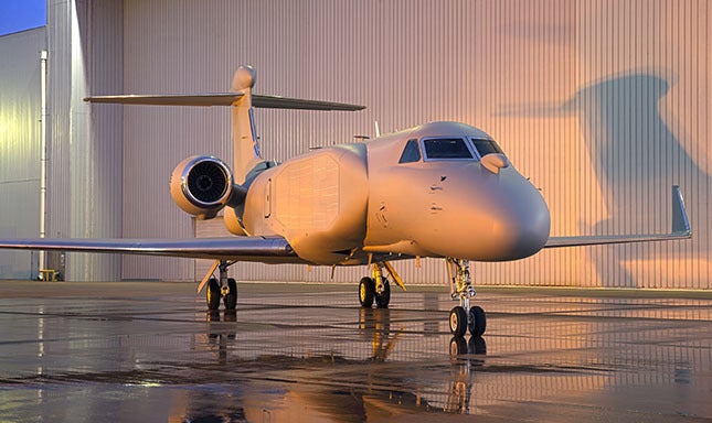 EA-37B Compass Call aircraft at dusk sits outside hangar