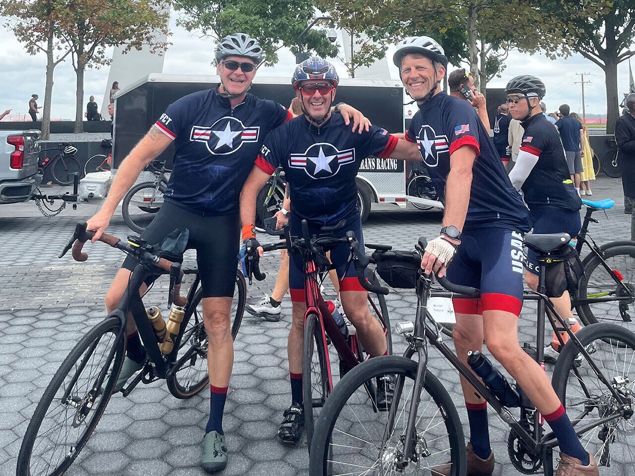 Three riders stand for a photo with their bicycles