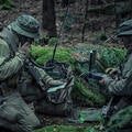 Soldiers using manpack radio in wooded area