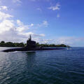 Submarine slices through water surface under a blue sky