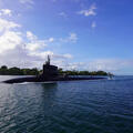 Submarine slices through water surface under a blue sky