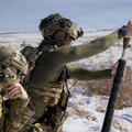 A Green Beret hangs a 60mm mortar round from a M225A mortar system on a live-fire range.