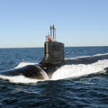 Submarine slices through water surface under a blue sky