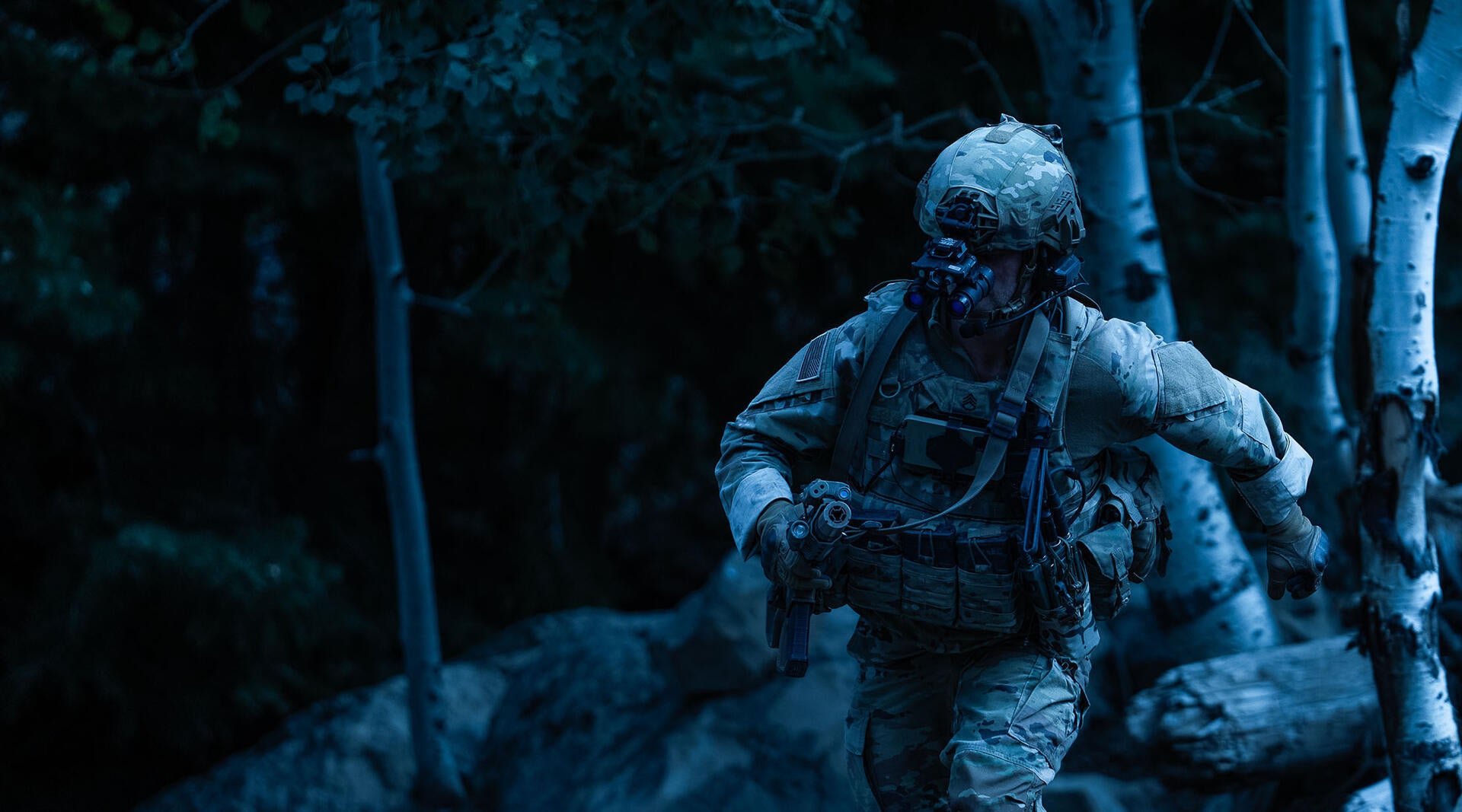 Soldier running through forest wearing night vision goggles