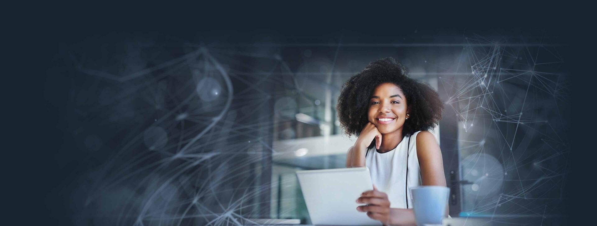 Young professional woman smiling at the camera while opening her laptop