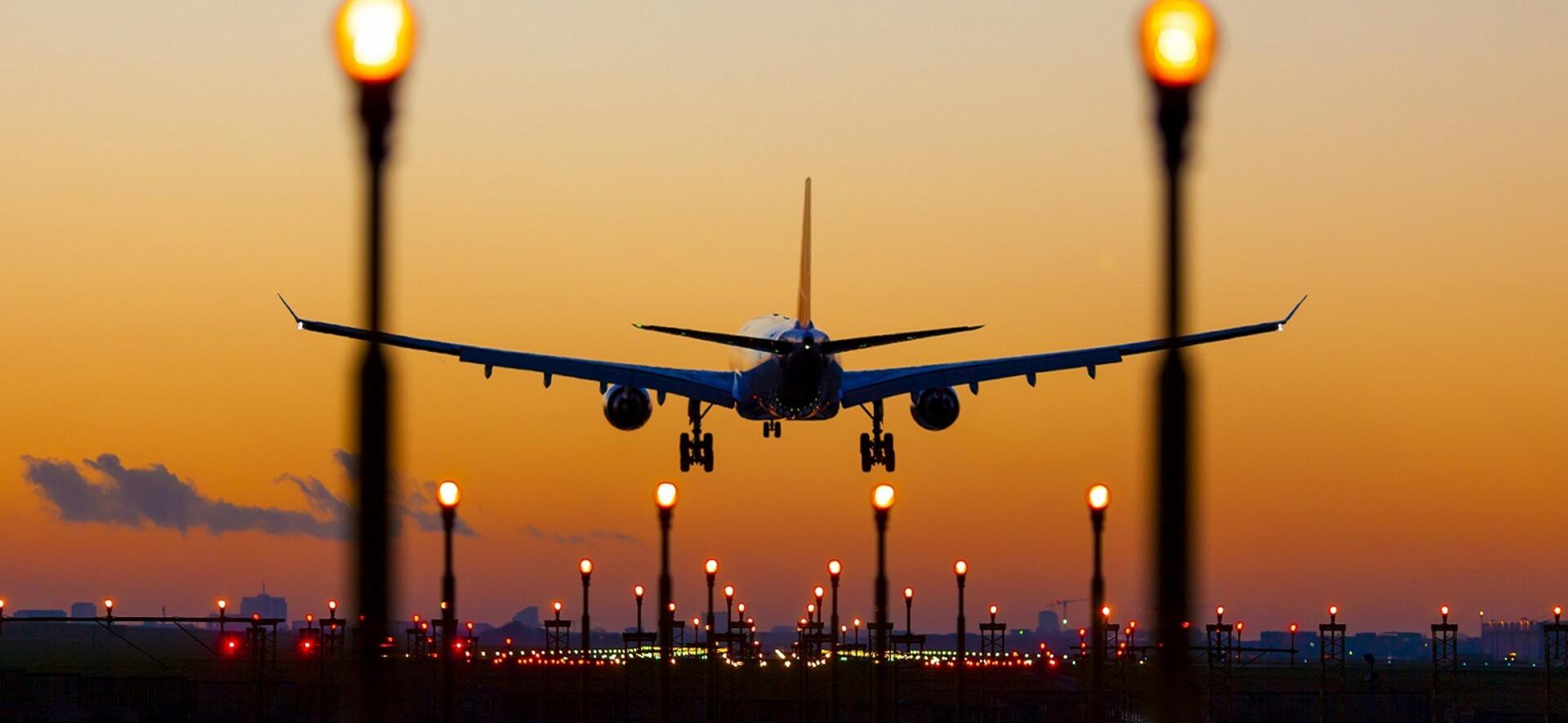 Commercial aircraft landing with sunset