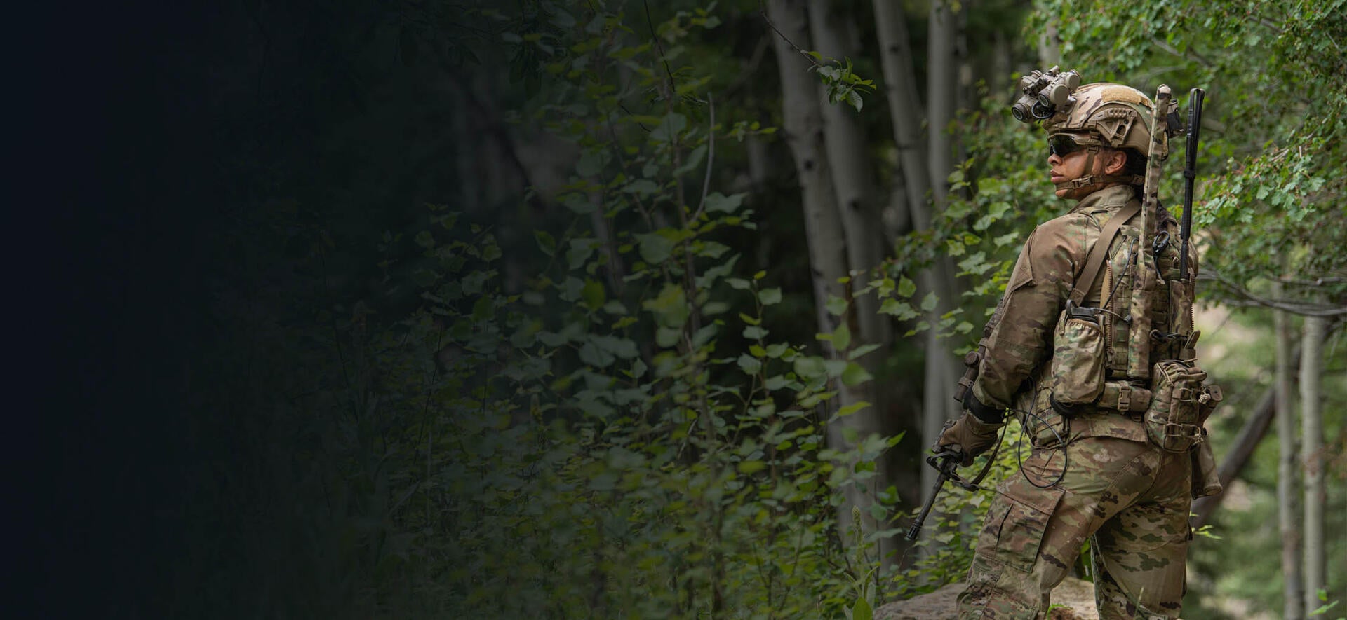 Soldier wearing communications equipment and night vision goggles in forest