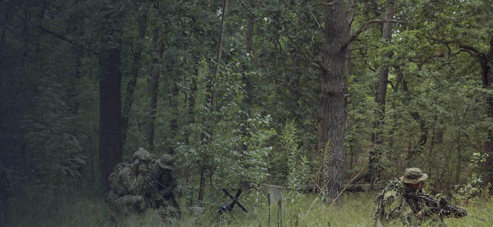 Polish soldiers in field talking on tactical communications radios