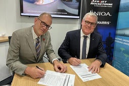 Two executives sign paperwork at a desk