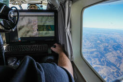 Worker types on laptop while looking out airplane window