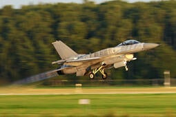 Jet takes off runway among green field