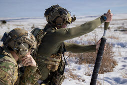 A Green Beret hangs a 60mm mortar round from a M225A mortar system on a live-fire range.