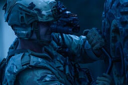 Soldier uses night vision goggles to assess a tire