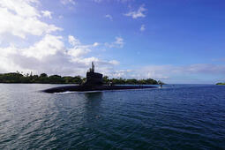 Submarine slices through water surface under a blue sky