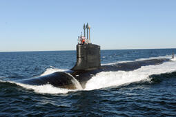 Submarine slices through water surface under a blue sky