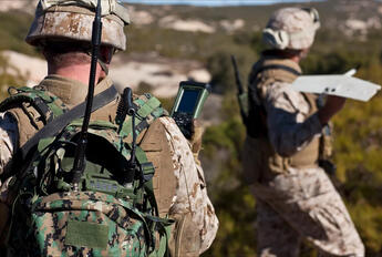 U.S. soldier in the field using a communication device. Image source: Shutterstock https://www.shutterstock.com/license