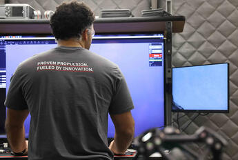 An employee looks at his screen in a T-shirt that says &quot;Proven Propulsion. Fueled by Innovation.&quot;