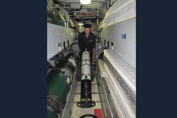 Sailor aboard USS DELAWARE turns an Iver4 900 AUV around for storage outside the torpedo room