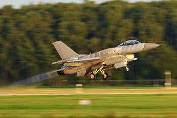 Jet takes off runway among green field