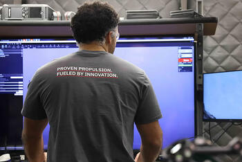 An employee looks at his screen in a T-shirt that says &quot;Proven Propulsion. Fueled by Innovation.&quot;