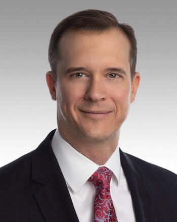 Jon Rambeau wears a suit and tie for a portrait