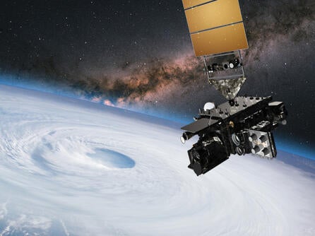 Satellite hovers in space over earth and the eye of a hurricane
