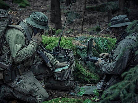 Soldiers using manpack radio in wooded area