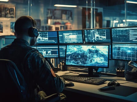 man in front of bank of computer screens