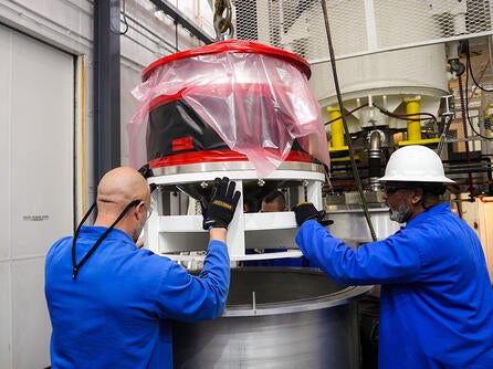 Employees maneuver a piece of hardware
