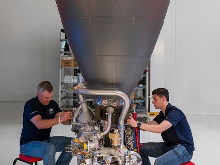 Two employees inspect an engine