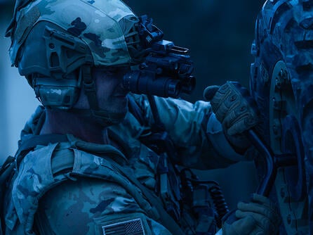 Soldier uses night vision goggles to assess a tire