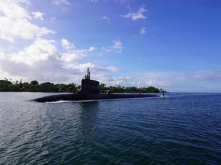 Submarine slices through water surface under a blue sky