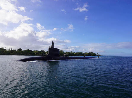 Submarine slices through water surface under a blue sky
