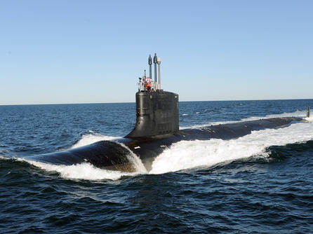 Submarine slices through water surface under a blue sky
