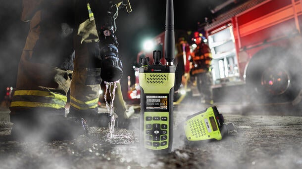 NFPA-compliant XL Extreme Fire Radio with firehose, firefighters and fire truck in background
