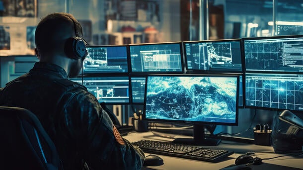 man in front of bank of computer screens