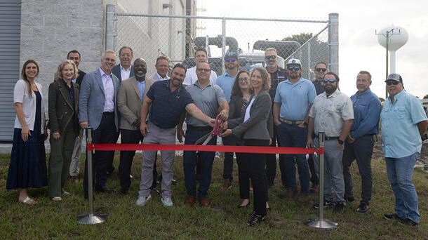 L3Harris employees cut a red ribbon at a facility