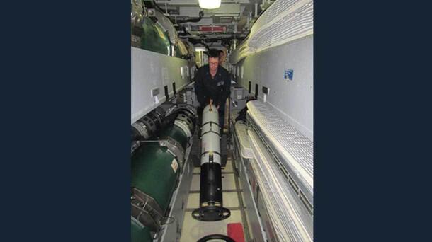 Sailor aboard USS DELAWARE turns an Iver4 900 AUV around for storage outside the torpedo room