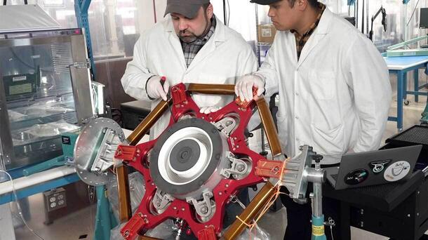 Two workers working on AEPS thrusters for NASA Glenn Research Center