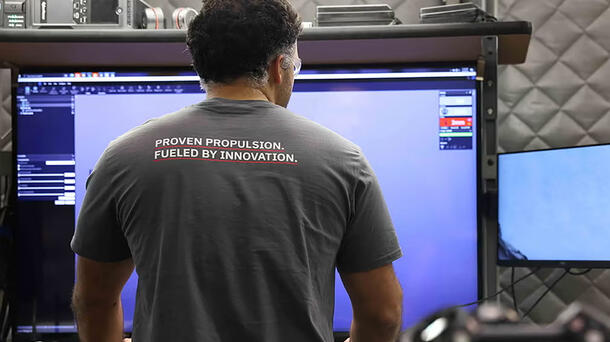 An employee looks at his screen in a T-shirt that says &quot;Proven Propulsion. Fueled by Innovation.&quot;