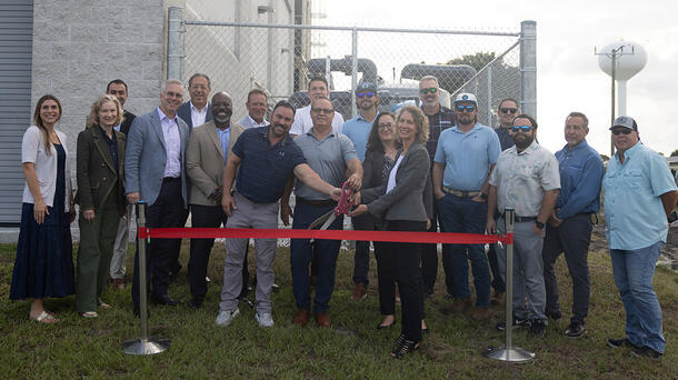L3Harris employees cut a red ribbon at a facility