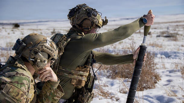 A Green Beret hangs a 60mm mortar round from a M225A mortar system on a live-fire range.
