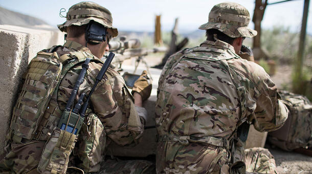 Soldiers with back to camera, one speaks through radio