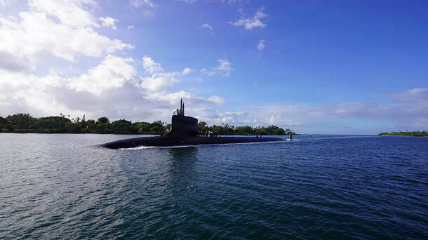 Submarine slices through water surface under a blue sky