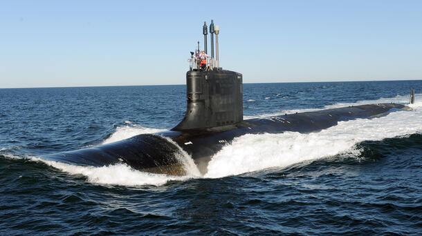 Submarine slices through water surface under a blue sky