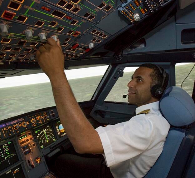 pilot inside simulator cockpit turning knobs