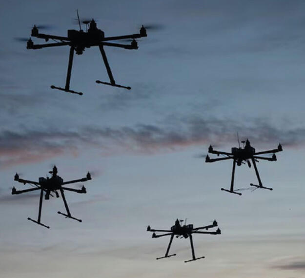 Multiple UAV drone copters flying with sunset sky behind them